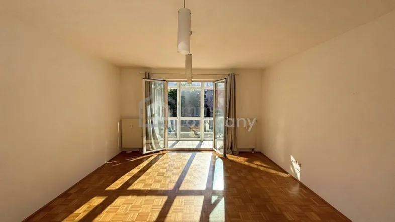 Helles Wohnzimmer mit Parkettboden und großen Glastüren, die viel Tageslicht hereinlassen.
