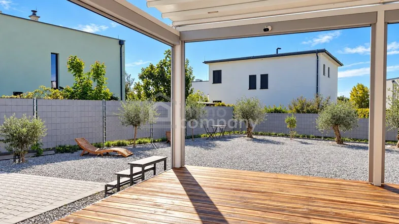Helle Holzterrasse mit moderner Pergola und Blick auf den Kiesgarten.