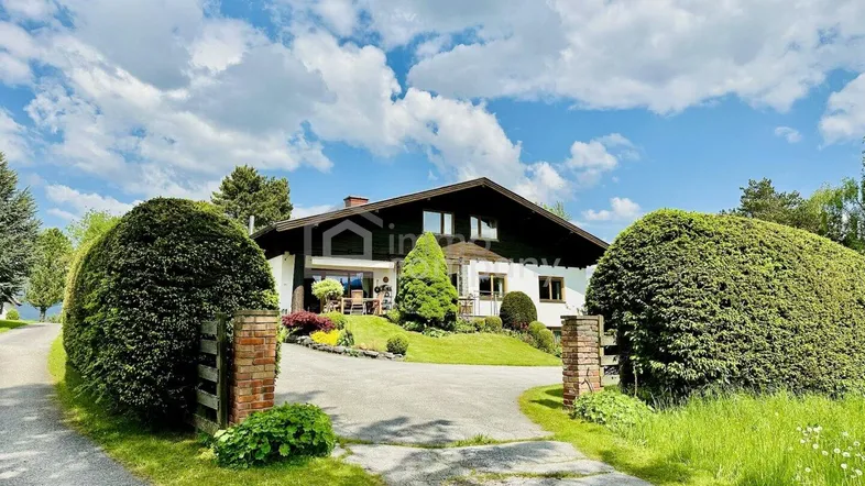 Großzügiges Anwesen mit gepflegtem Garten, Auffahrt und traditioneller Architektur unter blauem Himmel.