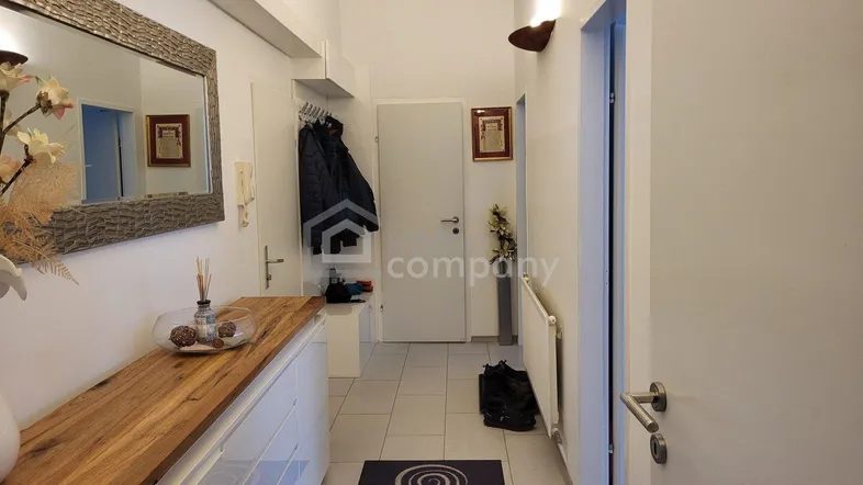Heller Flur mit moderner Holzkommode, großem Spiegel und praktischer Garderobe.
