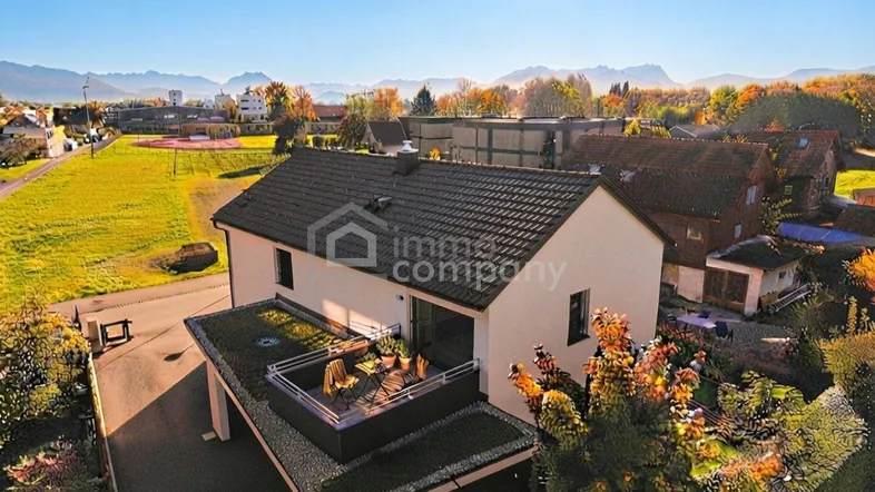 Luftaufnahme eines modernen Hauses mit Flachdach und Bergblick in sonniger Umgebung.