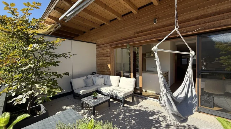 Geräumige Terrasse mit bequemen Gartenmöbeln, Hängesessel und Holzdecke für entspannte Stunden im Freien.