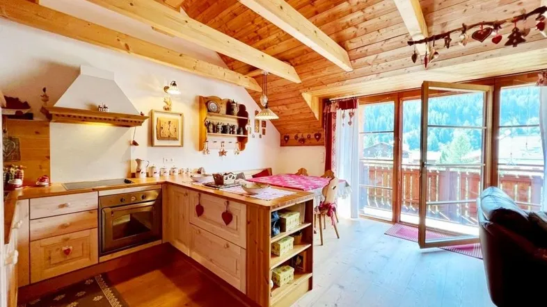 Gemütliche Küche im alpinen Stil mit Holzbalkendecke, Essbereich und Zugang zum Balkon mit Bergblick.