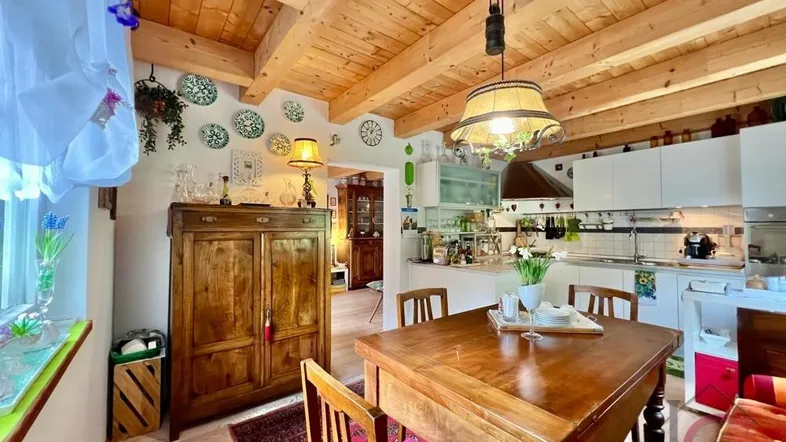 Gemütlicher Wohn-Essbereich mit Holzbalkendecke, traditionellen Möbeln und offener Küche.
