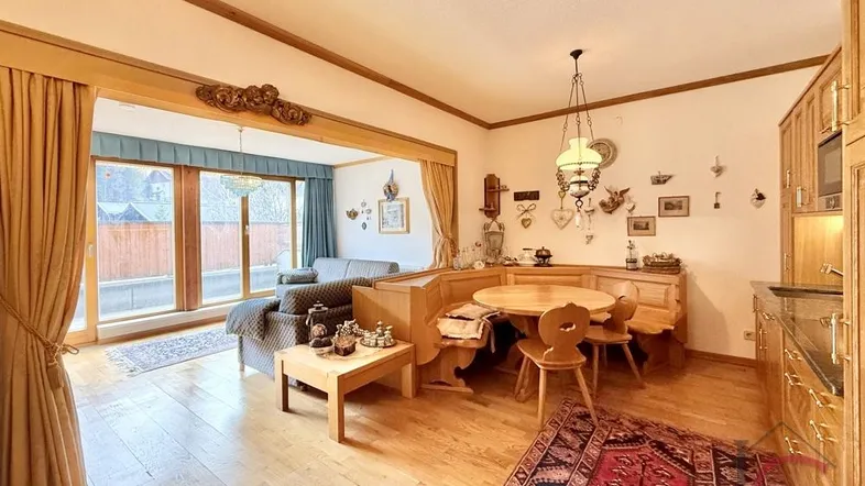 Gemütlicher Wohn- und Essbereich im alpinen Stil mit Holzboden und Zugang zum Außenbereich.