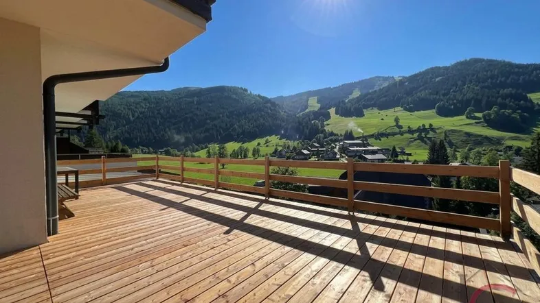 Große Holzterrasse mit Bergblick und viel Sonnenschein, ideal für entspannte Stunden im Freien.
