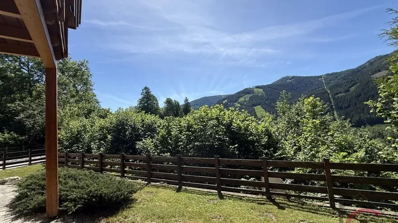 Überdachte Terrasse mit gepflastertem Boden und weitem Blick auf die umliegenden Berge.