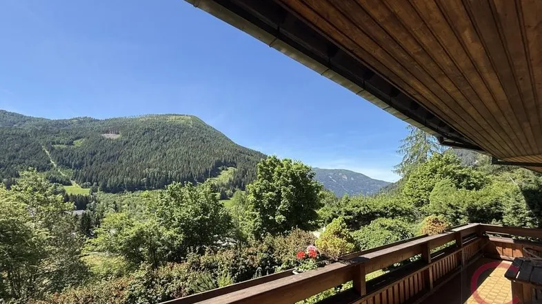 Geräumiger Balkon mit Holzboden und atemberaubendem Bergblick unter blauem Himmel.