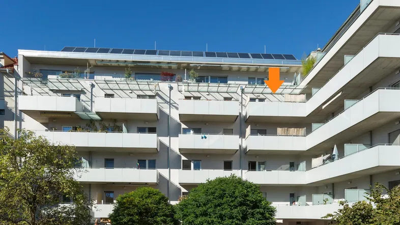 Moderne Wohnanlage mit mehreren Balkonen und Solarpaneelen auf dem Dach.