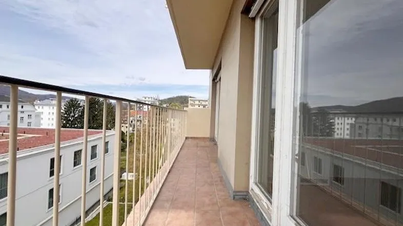 Langer Balkon mit Fliesenboden und Blick auf die umliegende Stadtlandschaft und Berge.