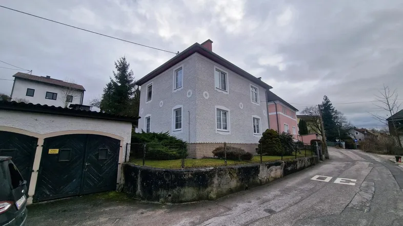 Ansicht des Wohnhauses von der Straße mit Garage und gepflegtem Vorgarten unter bewölktem Himmel.