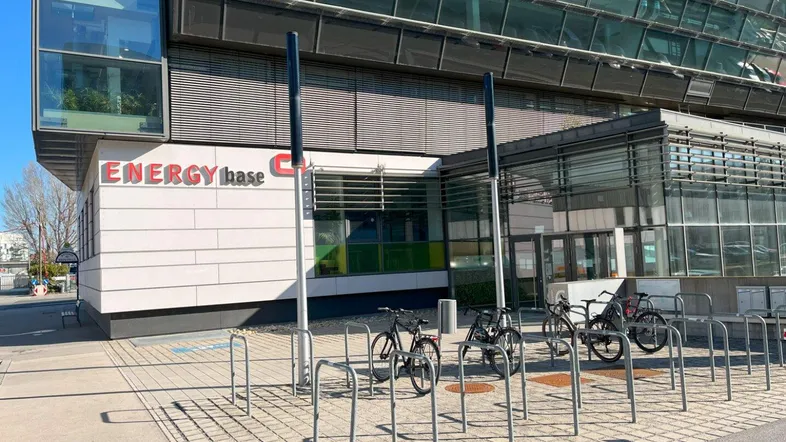 Moderne Bürogebäude-Fassade mit großen Glasflächen und Fahrradständern im Vordergrund unter blauem Himmel.