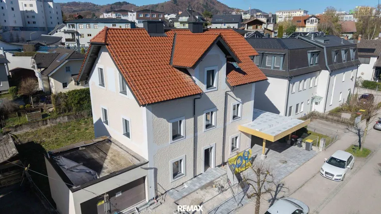 Luftaufnahme eines Hauses mit rotem Ziegeldach und hellem Anstrich in einer Wohngegend.