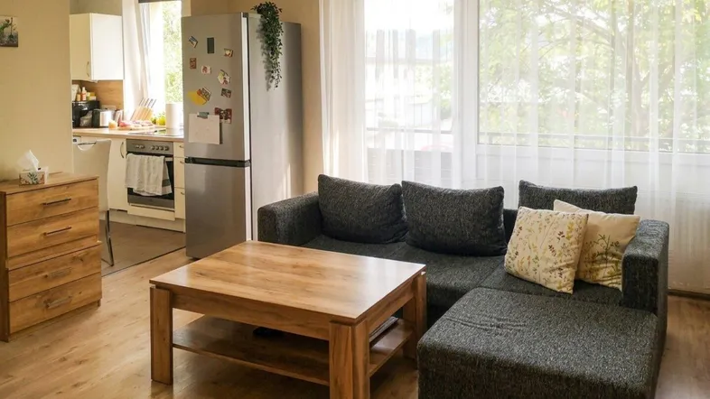Helles Wohnzimmer mit gemütlichem Sofa, Holztisch und Blick in die offene Küche.