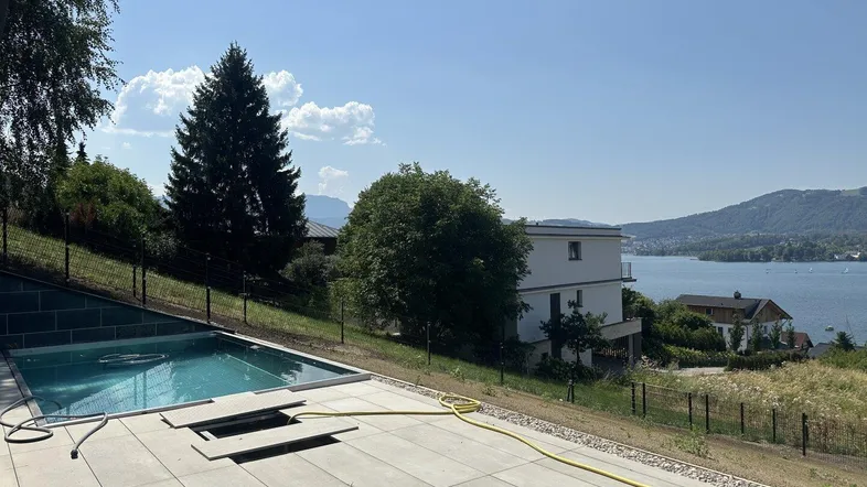 Große Terrasse mit modernem Pool und weitem Blick auf den See und die umliegenden Berge.