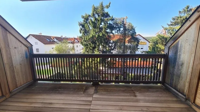 Geräumiger Balkon mit Holzboden und Holzgeländer, bietet einen grünen Blick auf die Umgebung.