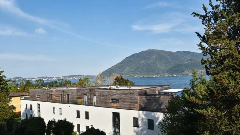 Moderne Wohnanlage mit Seeblick und Bergblick unter blauem Himmel.