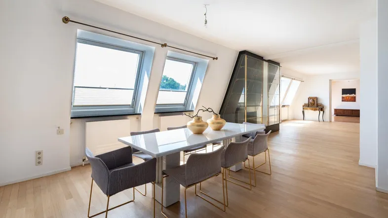 Helles Dachgeschoss-Wohnzimmer mit Esstisch, Parkettboden und schrägen Dachfenstern.
