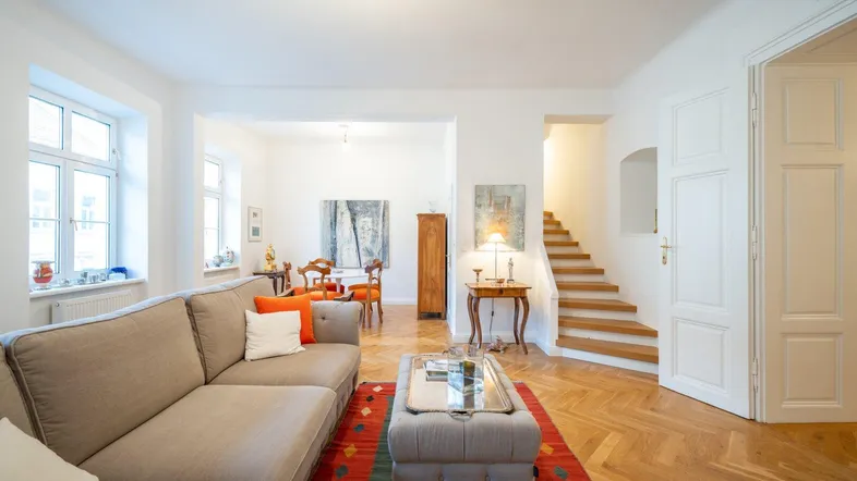 Geräumiges Wohnzimmer mit beigem Sofa, Parkettboden und offenem Übergang zum Essbereich.