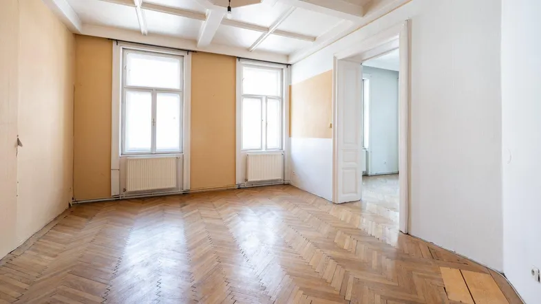 Geräumiges Zimmer mit Fischgrätparkett, hohen Decken und Stuckverzierungen, bereit zur individuellen Gestaltung.