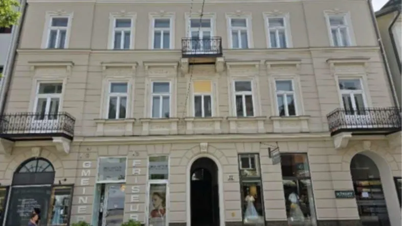Historisches Mehrfamilienhaus mit klassischer Fassade, dekorativen Elementen und Balkonen in städtischer Umgebung.