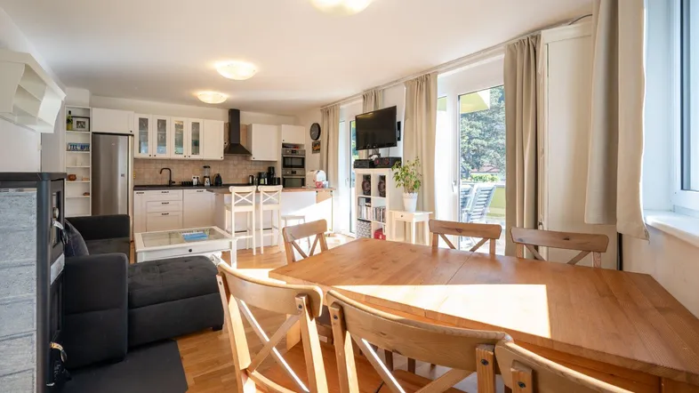 Heller offener Wohn-Essbereich mit integrierter Küche, Holzboden und Zugang zum Balkon.