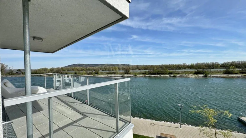 Geräumiger Balkon mit Fliesenboden und Glasgeländer, bietet einen weiten Blick auf den See.