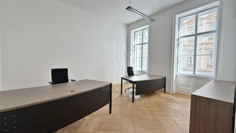 Helles Büro mit zwei Schreibtischen, Fischgrätparkett und Blick auf den Innenhof.