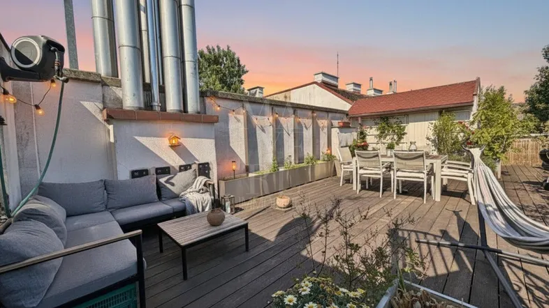 Geräumige Dachterrasse mit gemütlicher Lounge-Ecke, Esstisch und Pflanzen, ideal für entspannte Abende.