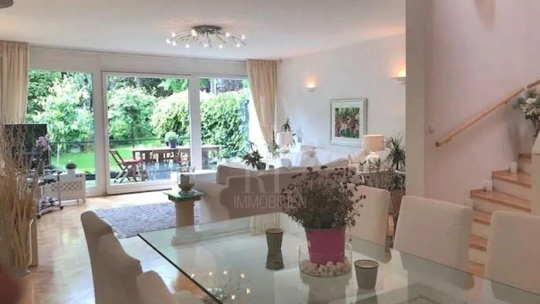 Heller Wohn- und Essbereich mit großen Fenstern, Blick in den Garten und Zugang zur Terrasse.