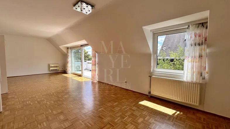Helles Wohnzimmer mit Parkettboden, Dachschrägen und Zugang zur Terrasse.