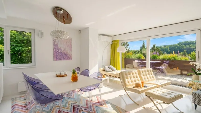 Helles Wohn- und Esszimmer mit modernen Möbeln, farbigem Teppich und Zugang zur Terrasse.
