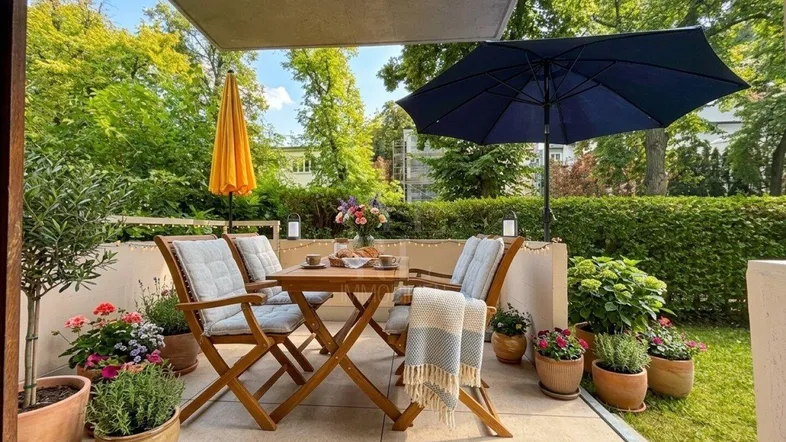Gemütliche Terrasse mit Holztisch, Stühlen und Sonnenschirm, umgeben von viel Grün.