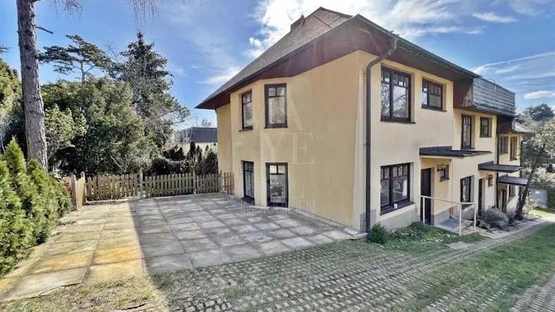Geräumiges Einfamilienhaus mit gepflegter Fassade, großem Vorplatz und umgebendem Garten.