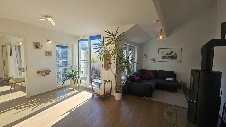 Helles Wohnzimmer mit Holzboden, modernem Kaminofen und Zugang zu einem sonnigen Balkon.