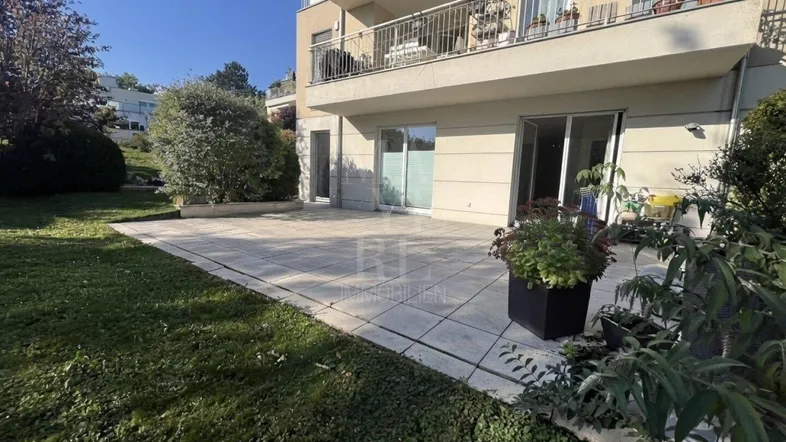 Große gepflasterte Terrasse mit direktem Zugang zum Garten und Blick auf das Gebäude.