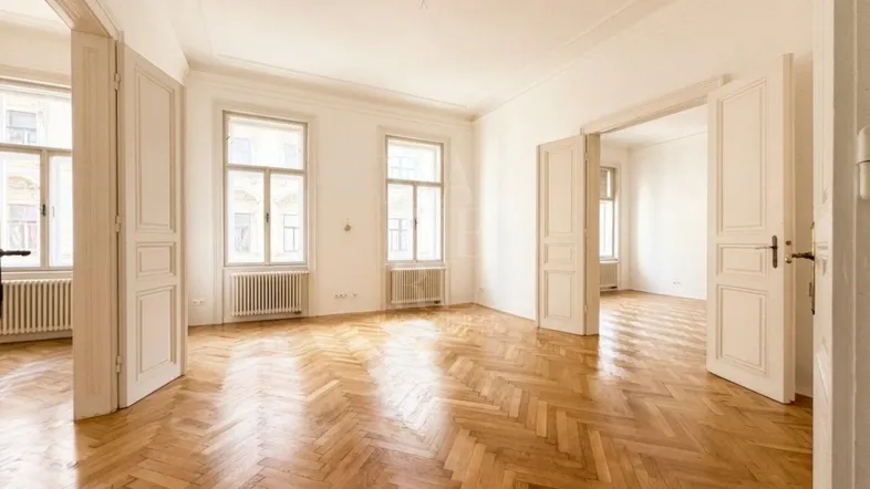 Helles, geräumiges Zimmer mit Fischgrätparkett, hohen Decken und mehreren Fenstern, das vielseitig nutzbar ist.