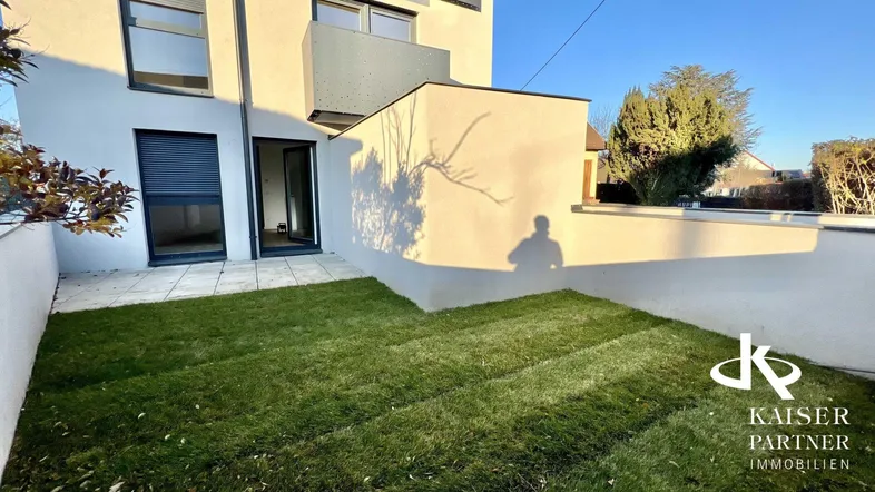 Kleiner Gartenbereich mit Rasenfläche und Zugang zur Terrasse am modernen Gebäude.