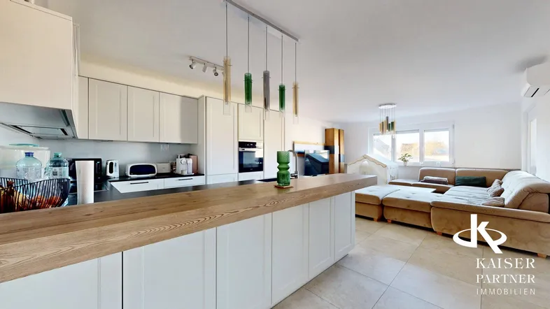 Moderne offene Küche mit Holztheke und angrenzendem Wohnbereich mit beigem Sofa.