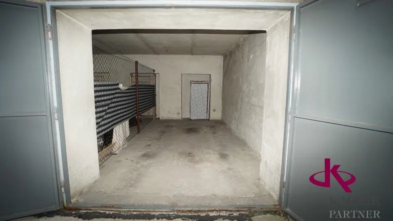 Geräumiger Garagenplatz mit Betonboden und Zugang zu einem separaten Lagerbereich.