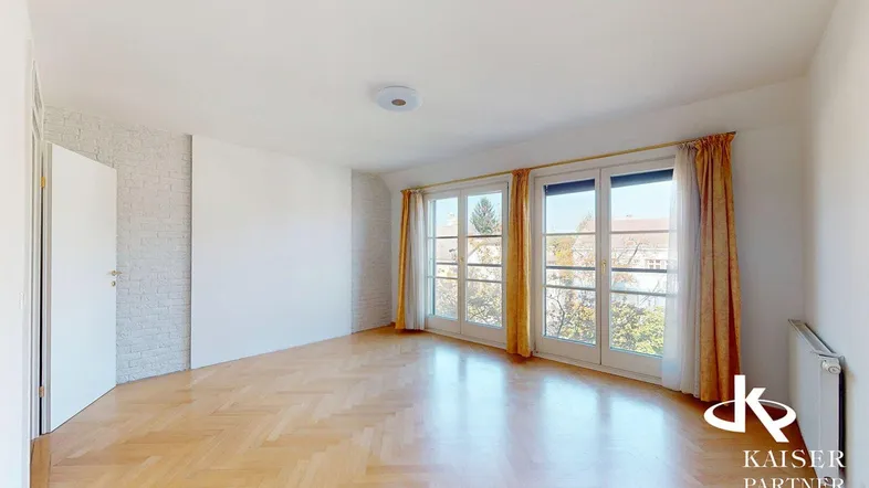 Geräumiges Zimmer mit hellem Fischgrätparkett und großen Fenstern, ideal als Wohn- oder Schlafzimmer.