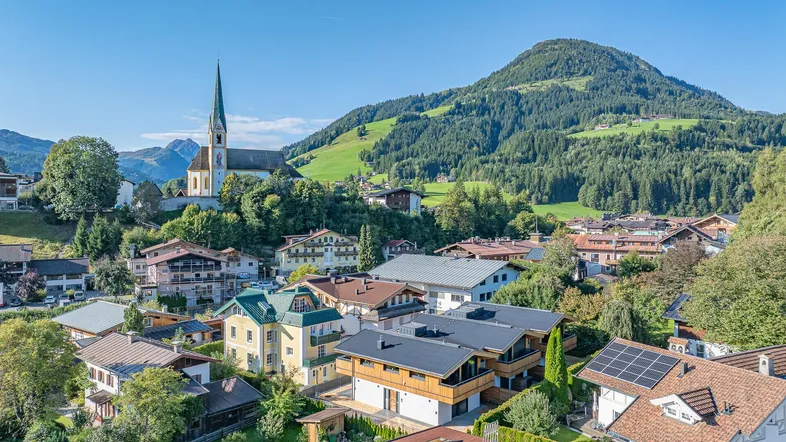 Panoramablick auf ein malerisches Dorf in den Bergen mit traditionellen Häusern und einer Kirche.