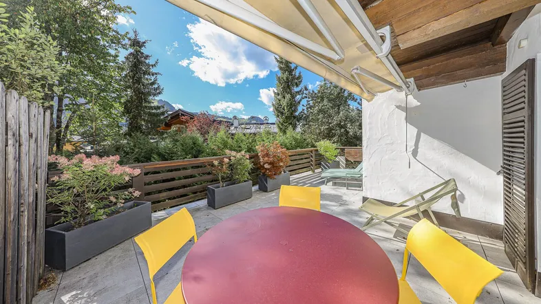 Geräumige Terrasse mit Gartenmöbeln, Markise und Blick auf die umliegende Berglandschaft.