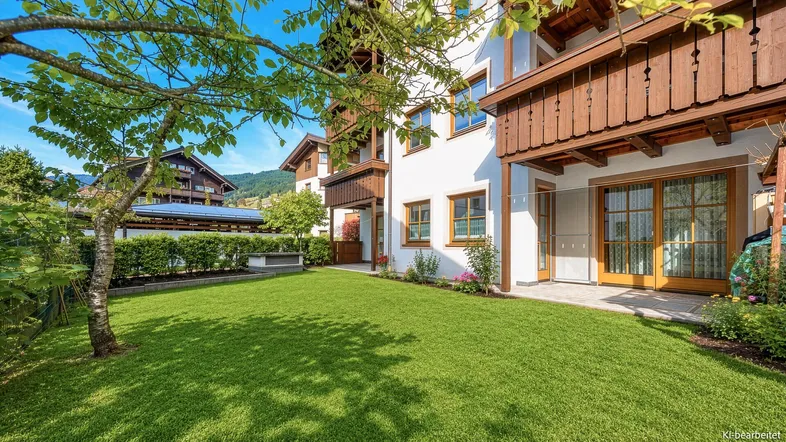 Gepflegter Gartenbereich mit Rasenfläche und Zugang zur Terrasse eines traditionellen Wohnhauses.
