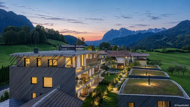 Moderne Wohnanlage mit begrünten Dächern und Bergblick bei Sonnenuntergang.