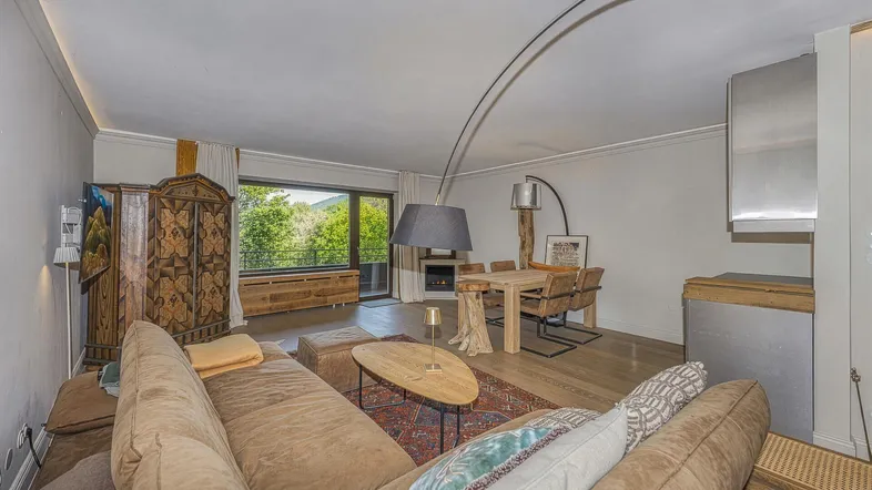 Geräumiger Wohn- und Essbereich mit Holzboden, Kamin und Bergblick durch große Fenster.