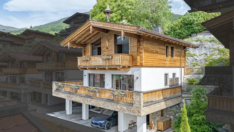 Traditionelles Holzchalet mit Balkonen und Carport in alpiner Umgebung.