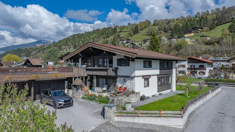 Traditionelles Haus im alpinen Stil mit gepflegtem Vorgarten und Bergblick.