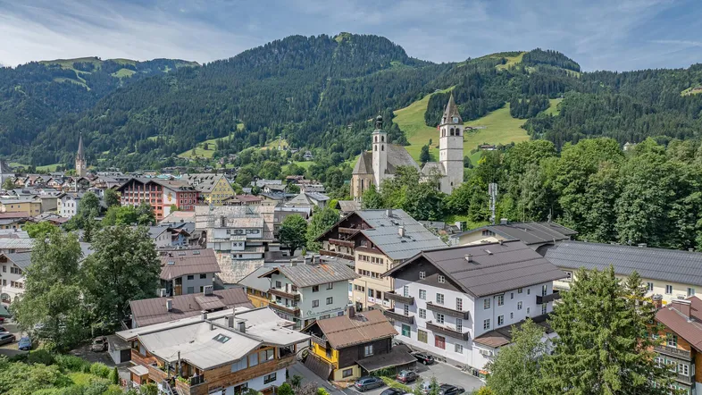 Panoramablick auf die Stadt mit traditionellen Gebäuden und majestätischen Bergen im Hintergrund.