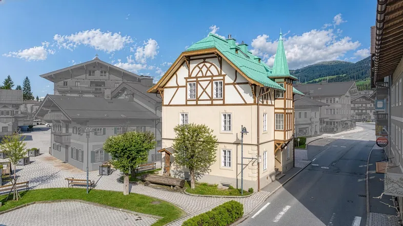 Traditionelles Gebäude im alpinen Stil mit markantem grünen Dach und Fachwerkelementen in einer Berglandschaft.